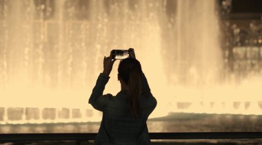 Çekici bir turist kızın fıskiyelerin fotoğrafını ya da videosunu çekmesi.