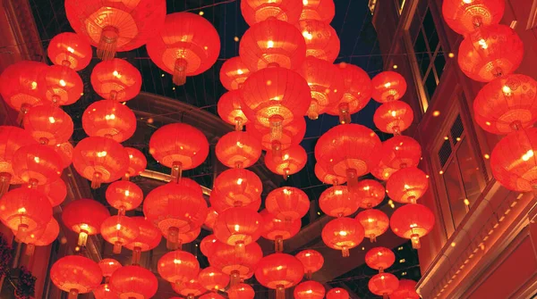 Kırmızı yanan Çin fenerleri bir şehir caddesi boyunca havaya yükseliyor.