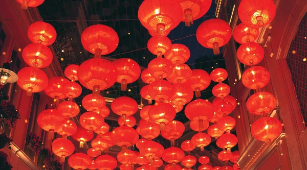 Red burning chinese lanterns rise into the air along a city street