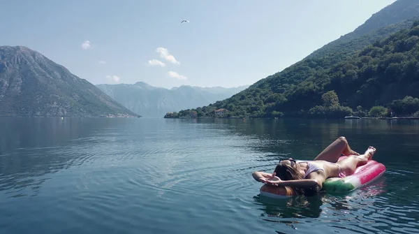 AÉRIAL. Les jeunes femmes aiment flotter sur un matelas à la mer. Montagnes sur fond. — Photo