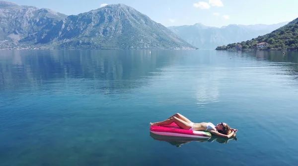 AÉRIAL. Les jeunes femmes aiment flotter sur un matelas à la mer. Montagnes sur fond. — Photo