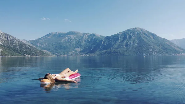 AÉRIAL. Les jeunes femmes aiment flotter sur un matelas à la mer. Montagnes sur fond. — Photo