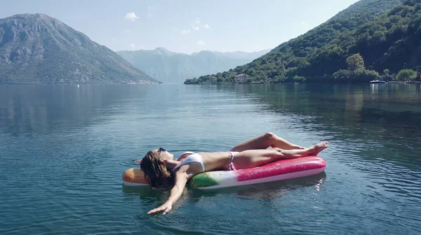 AÉRIAL. Les jeunes femmes aiment flotter sur un matelas à la mer. Montagnes sur fond. — Photo