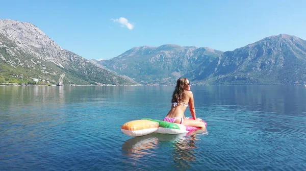 AÉRIAL. Les jeunes femmes aiment flotter sur un matelas à la mer. Montagnes sur fond. — Photo