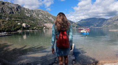 İskelede yürüyen kimliği belirsiz güzel genç bir kadın turistin arka görüntüsü.