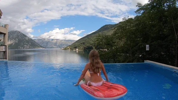 Mayo ve güneş gözlüğü takmış ince, beyaz, sarışın bir kadın.