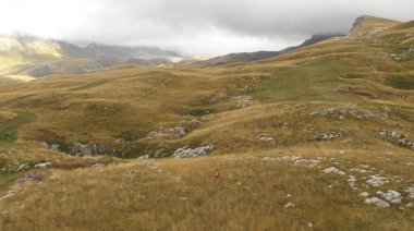 Tepeler boyunca yürüyen yalnız bir genç turist görüntüsü.