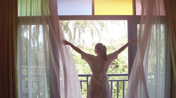 Belle femme ouvrant des rideaux colorés et rencontrant le lever du soleil. Vue du balcon à la jungle. — Photo