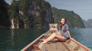 Genç Mutlu Karışık Yarış Kızı Khao Sok Gölü 'nde geleneksel Tayland Tahta Teknesinde oturup dinleniyor. Phang Nga Eyaleti, Tayland.