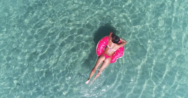AERIÁLIS. Top kilátás fiatal csinos csinos lány úszás rózsaszín úszómatrac az óceánon, visel bikini és napszemüveg, kilátás az óceánra, pihenjen és szórakozás nyaralás. — Stock Fotó
