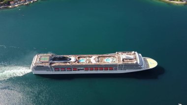 AERİAL. Yüksek uçuş ve büyük lüks yolcu gemisinin üst görüntüsü hava görüşünde gün doğumunda liman kanalından denize açılmaya devam ediyor.