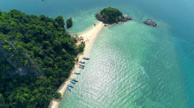 Hava. Tropikal ada beyazının turkuaz plaj lagününün ve Krabi ufkundaki adaların kayalıklarının en üst görüntüsü, zümrüt su üzerindeki iki uzun kuyruklu teknenin sahili veya üst görüntüsü.