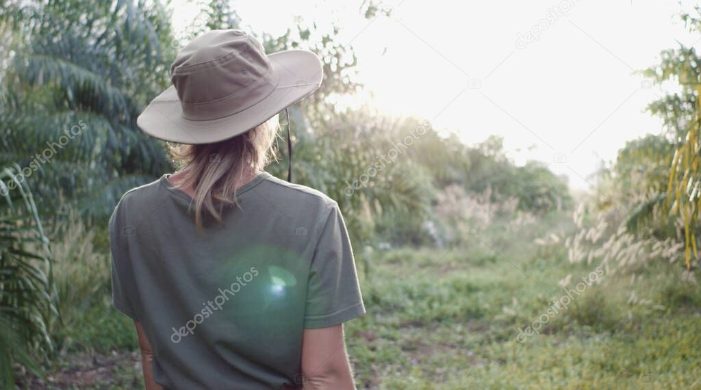 Back view of woman tracking and camping in forest, bluring background.