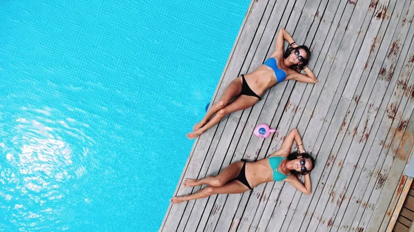 L'air. Drone photo de deux belles filles sexy dans un élégant maillot de bain relaxant au bord de la piscine dans une villa de luxe — Photo
