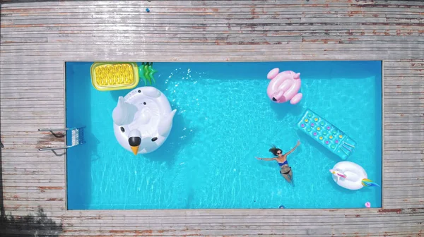 AÉRIAL. femme s'amuser sur le matelas gonflable dans la piscine. Différents lits gonflables de différentes couleurs et formes — Photo