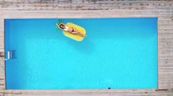 Vue aérienne de la femme sur matelas gonflable en forme d'ananas dans la piscine. — Photo