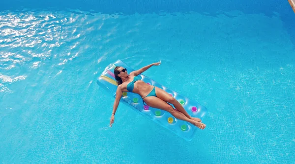 Style de vie en plein air portrait de jeune jolie fille sexy flottant avec matelas lumineux néon près de la piscine — Photo