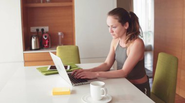 Evde dizüstü bilgisayarı olan güzel sarışın kadın.