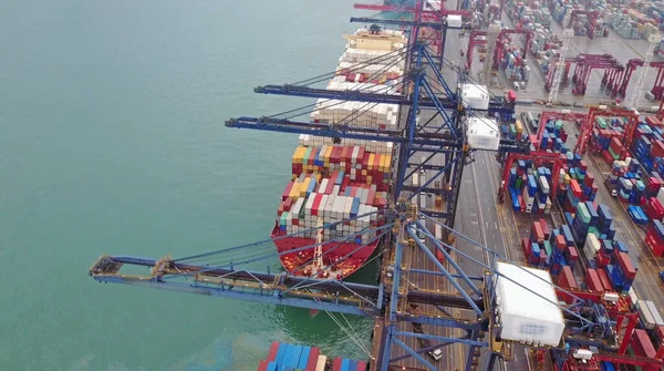 Размыл все видимые марки. Вид с воздуха на огромный промышленный порт с контейнерами и огромным кораблем. — стоковое фото