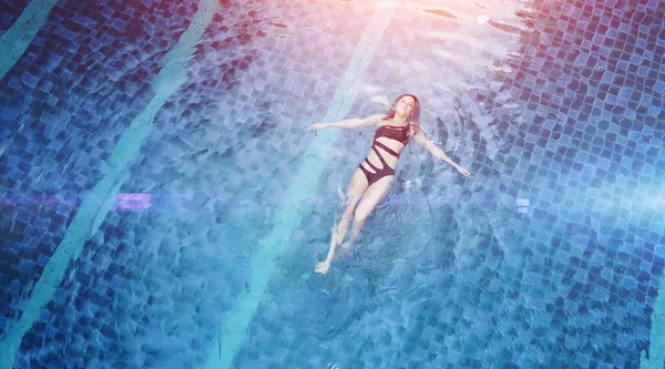 La photo aérienne d'un séduisant modèle sexy en maillot de bain noir profite de la détente dans la piscine de l'hôtel. Femme de mode incroyable en bikini ayant un repos spa de luxe — Photo