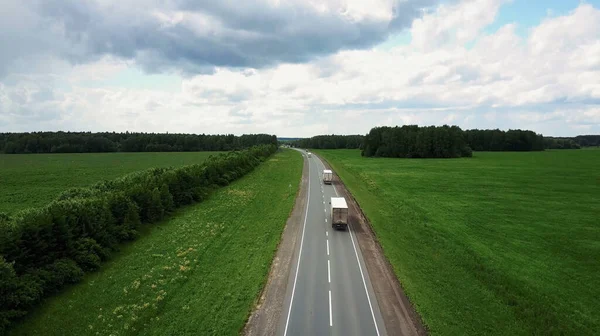 Prachtig landschap met een ritje op de snelweg de vrachtwagens en een paar auto 's bij zonsondergang. vanuit de lucht bekeken — Stockfoto