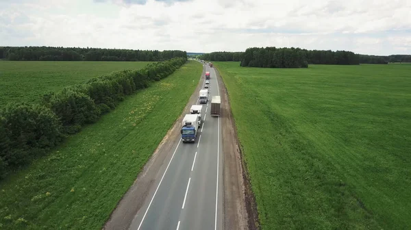 Prachtig landschap met een ritje op de snelweg de vrachtwagens en een paar auto 's bij zonsondergang. vanuit de lucht bekeken — Stockfoto