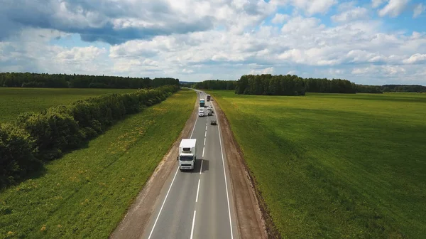 Prachtig landschap met een ritje op de snelweg de vrachtwagens en een paar auto 's bij zonsondergang. vanuit de lucht bekeken — Stockfoto