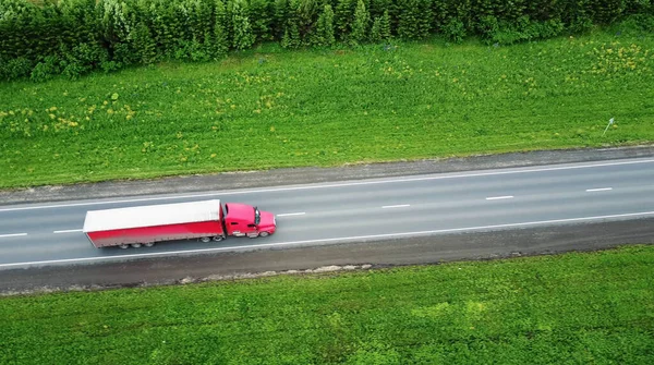 Vrachtwagens die naar de zon rijden. Luchtfoto van groene velden en vrachtwagens — Stockfoto