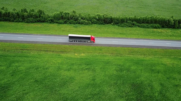 รถขนส่งกําลังมุ่งหน้าไปยังดวงอาทิตย์ มุมมองทางอากาศ f สนามสีเขียว snd รถบรรทุก — ภาพถ่ายสต็อก