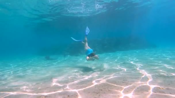 Jonge mooie vrouw bij blauw zwempak draaiend onder water aan de rode zee met zonnevlam en kristalhelder oceaanwater. — Stockvideo