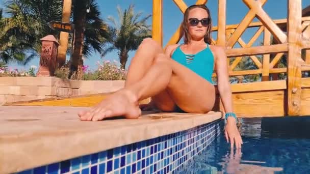 熱帯映像、女性は豪華なホテルでスイミングプールの近くに座っている。旅行夏のコンセプト. — ストック動画