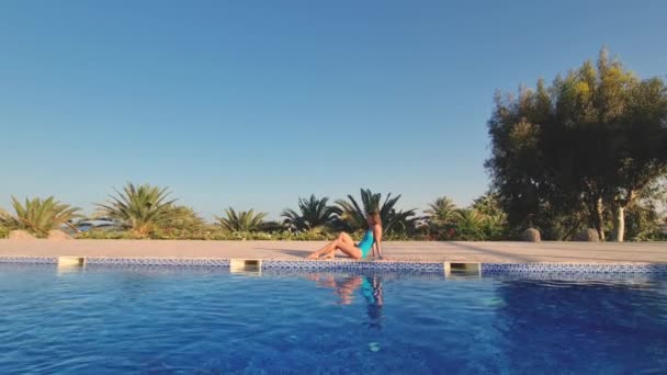 Jeune femme sexy se trouve près de la piscine et de la plage. Caméra zoomant sur la jeune fille vêtue de maillot de bain bleu . — Video