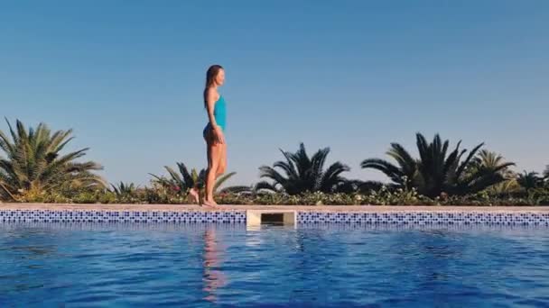 Young woman walks at the side of swimming pool — Stock Video