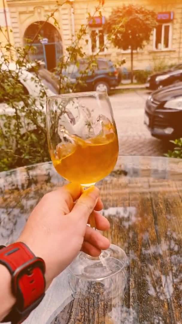 Långsam rörelse POV man hand hålla glas vin med bakgrund av stadsbilden. Vertikala bilder. — Stockvideo