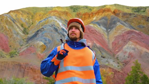 Porträtt av en gruvingenjör, geolog i skyddsväst, handskar och hjälm, med hammare i handen. — Stockvideo