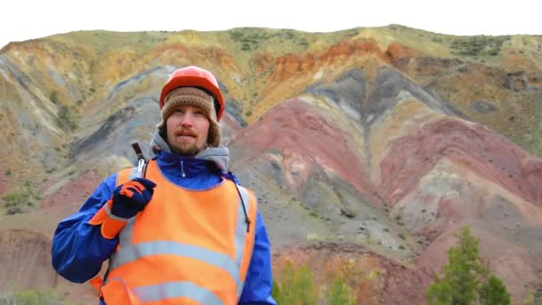 Film - Porträtt av en gruvingenjör, geolog i skyddsväst, handskar och hjälm, med hammare i handen. — Stockvideo