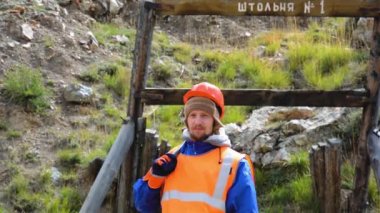 Maden mühendisi, koruyucu yelek giyen bir jeolog, eldiven ve miğfer, elinde çekiçle..