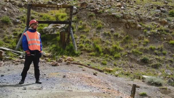 Gruvingenjör, geolog i skyddsväst, handskar och hjälm, med hammare i handen. — Stockvideo