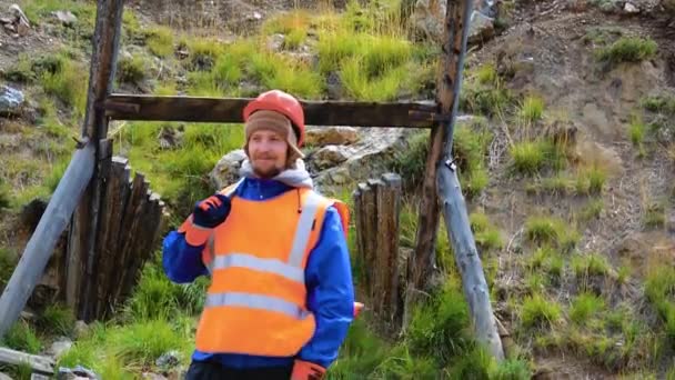 Горный инженер, геолог в защитном светоотражающем жилете, перчатках и шлеме, с молотком в руке. — стоковое видео