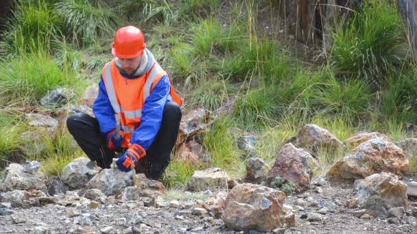 Un ingeniero minero o geólogo que usa guantes, un casco, un chaleco reflectante — Vídeo de stock