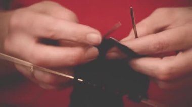 Örgü iğneleriyle yakın çekim eller, güzel bir kadın örgü örer.