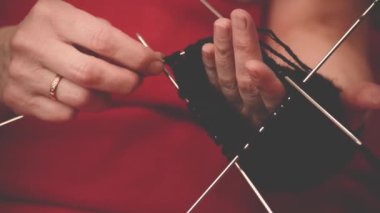 Örgü iğneleriyle yakın çekim eller, güzel bir kadın örgü örer.