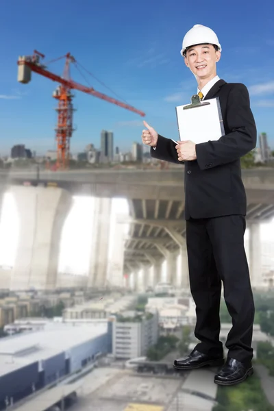 Young Male Engineer in Black Suit and White Helmet holding check