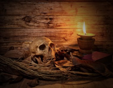 ahşap sekmesinde kuru yaprak ve mum ışığı ile kafatası natürmort