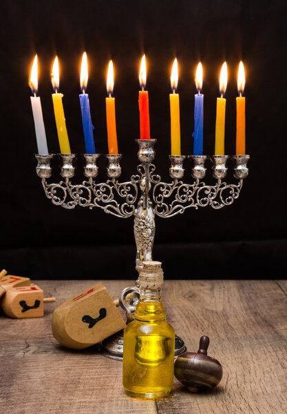 Dreidels and small jug of oil and  a menorah. Hanukkah