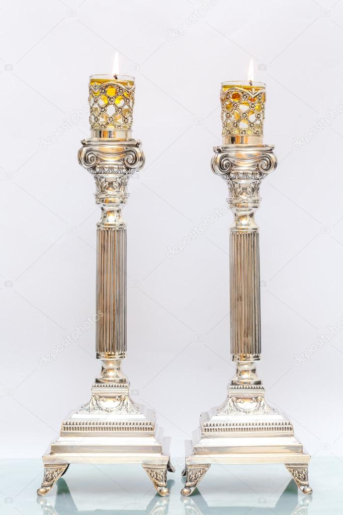 Shabbat candles. Silver candlesticks with olive oil. Light background