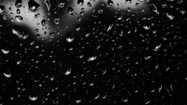 Islak cam. Su damlacıkları. Kapalı camlara yağmur damlaları düşer. Seçici odak siyah ve beyaz
