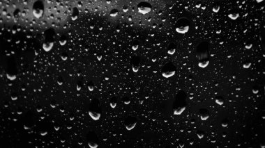 Islak cam. Su damlacıkları. Kapalı camlara yağmur damlaları düşer. Seçici odak siyah ve beyaz