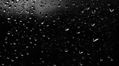 Islak cam. Su damlacıkları. Kapalı camlara yağmur damlaları düşer. Seçici odak siyah ve beyaz