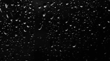 Islak cam. Su damlacıkları. Kapalı camlara yağmur damlaları düşer. Seçici odak siyah ve beyaz